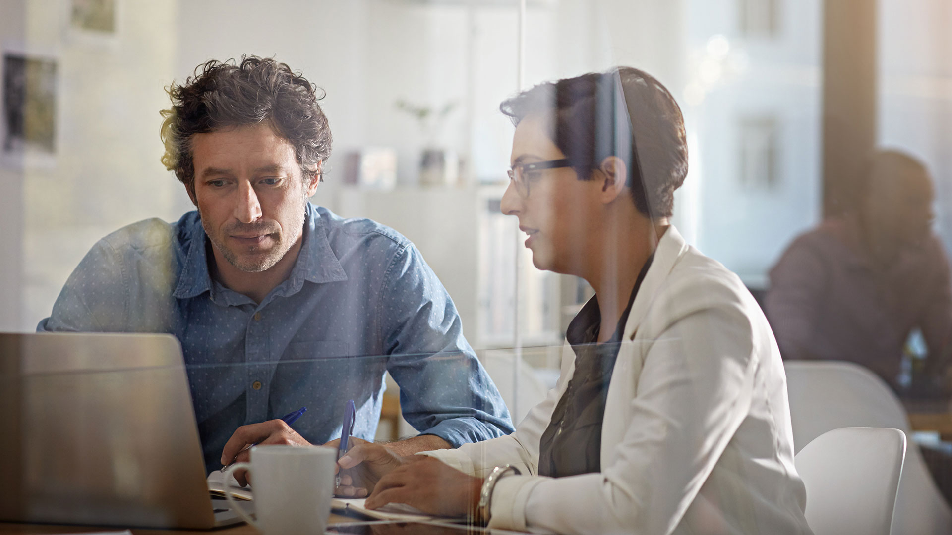 Two co-workers talking in a conference room.