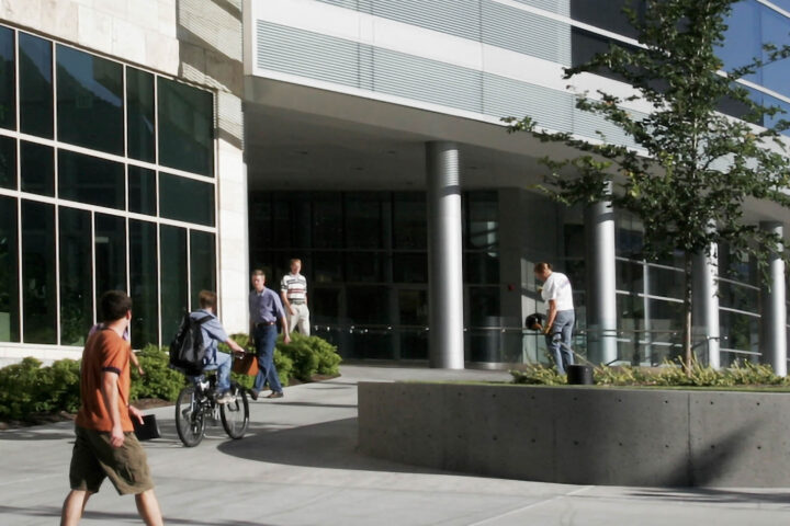pedestrians walk by a modern building of a company